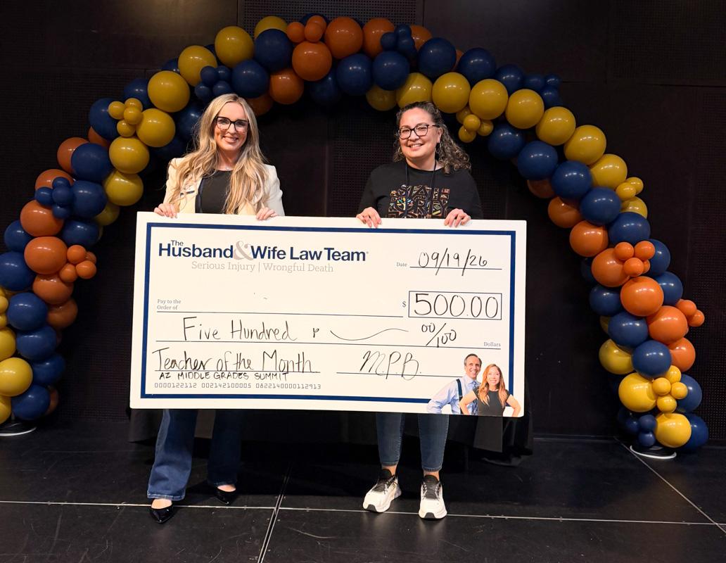 Jen from the Husband & Wife Law Team presents Ms. Lozano with a $500 Teacher of the Month award, recognizing her dedication, leadership, and positive impact on students.