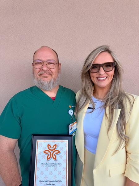 Framed certificate in hand, Jody stands tall next to a Husband & Wife Law Team representative, both sharing a triumphant smile.