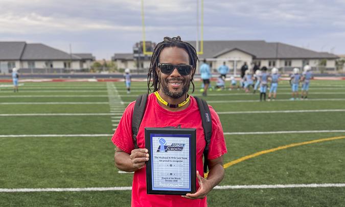 Celebrating an outstanding leader! Coach Edwards proudly accepts his Husband & Wife Law Team Coach of the Month recognition on the field.