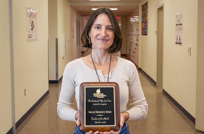 Mrs. Vargas-Portley proudly displays her Teacher of the Month award at Kenny Elementary School, celebrating her dedication and positive impact on students.