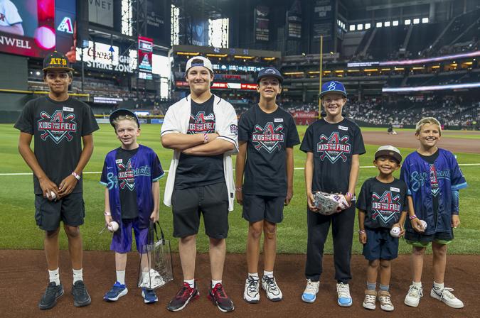 Seven Kids Take the Field participants gather on the field with big smiles, sharing the excitement of a once-in-a-lifetime experience at Chase Field before the game.
