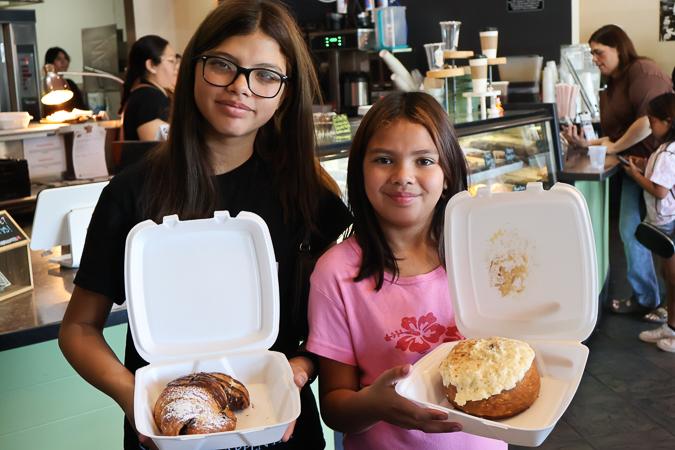 Two young attendees show off their delicious pastries at the Husband & Wife Law Team's HEART event at Downtown Chandler Cafe & Bakery, enjoying a morning of community connection and sweet treats.