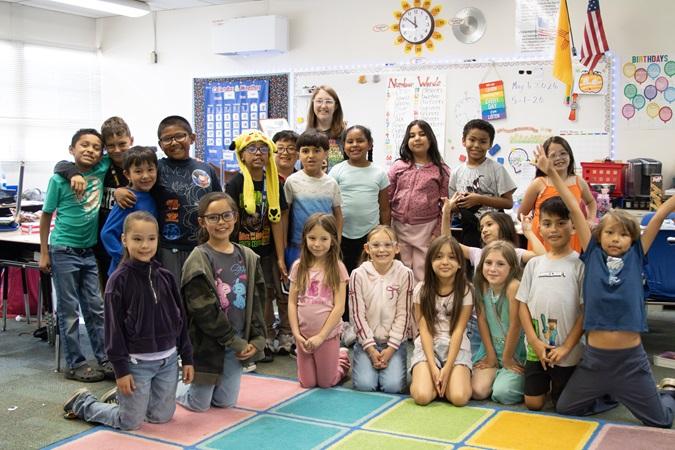 Ms. Noble and Zuni students pose together in a colorful classroom.