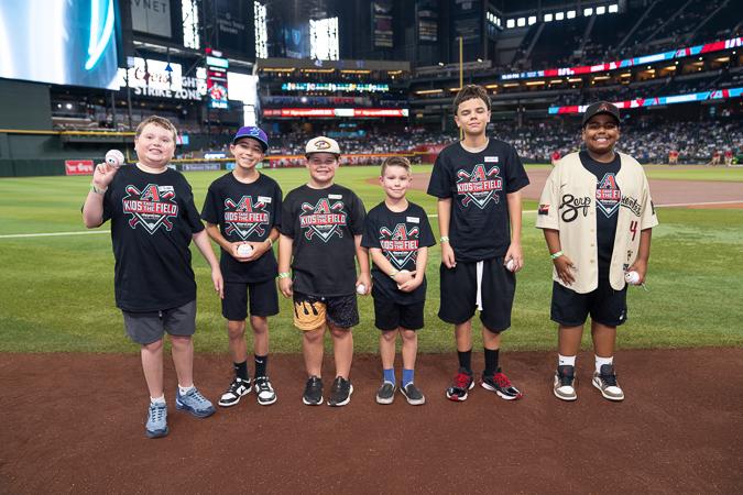 Six Kids Take the Field winners gather on Chase Field with baseballs in hand, celebrating an unforgettable experience at the home of the Arizona Diamondbacks.
